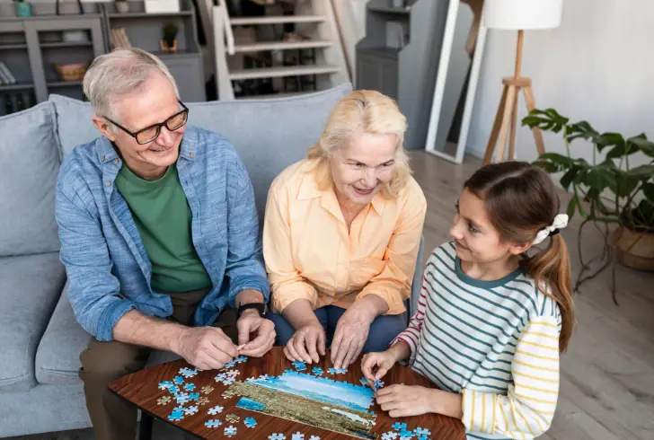An older couple solving a puzzle with grandchildren